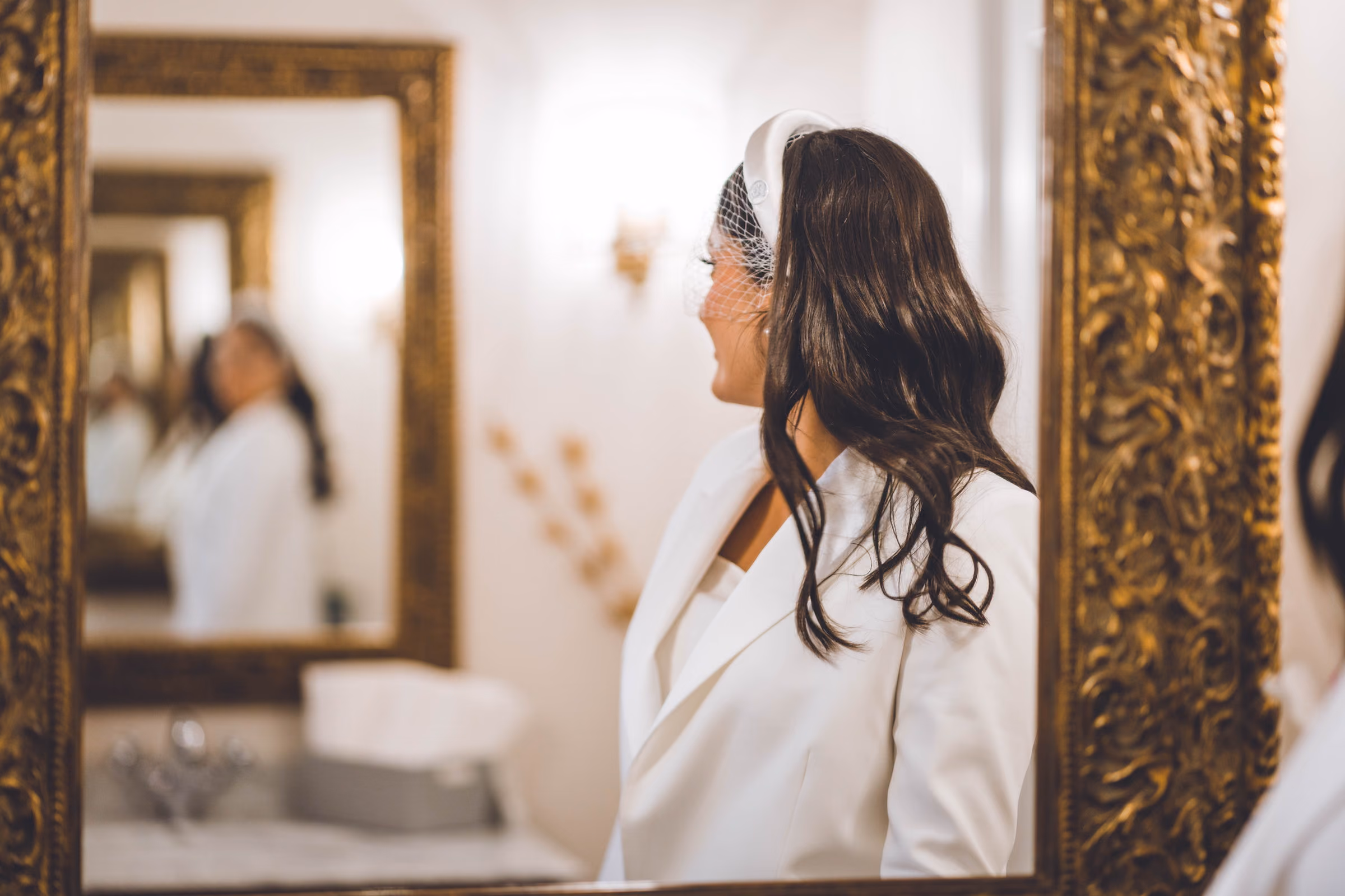 The bride in profile before a mirror, a headband in her hair