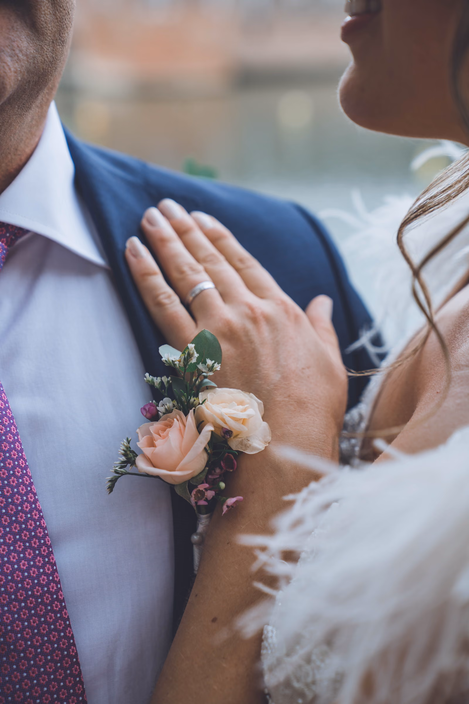 The couple’s hands against one another, the buttonhole in the foreground