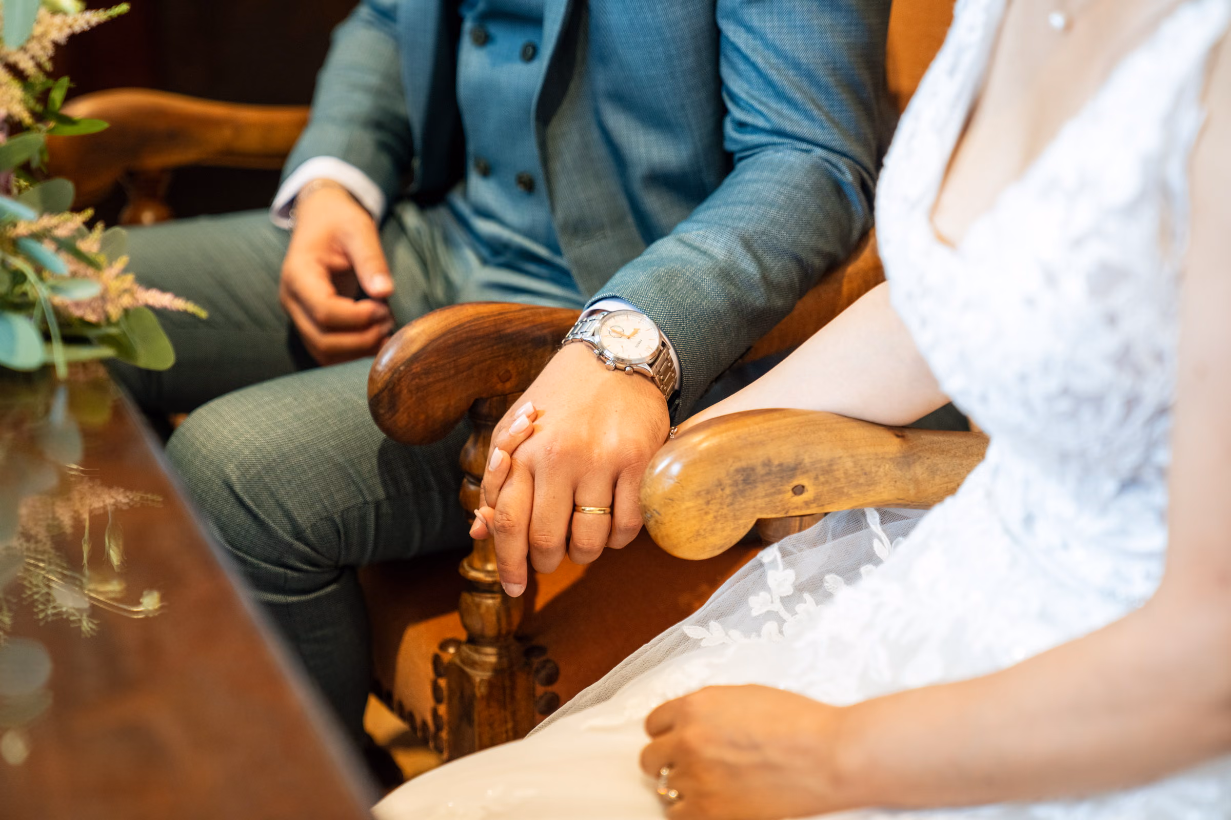 The couple seated side by side during the ceremony, hands joined