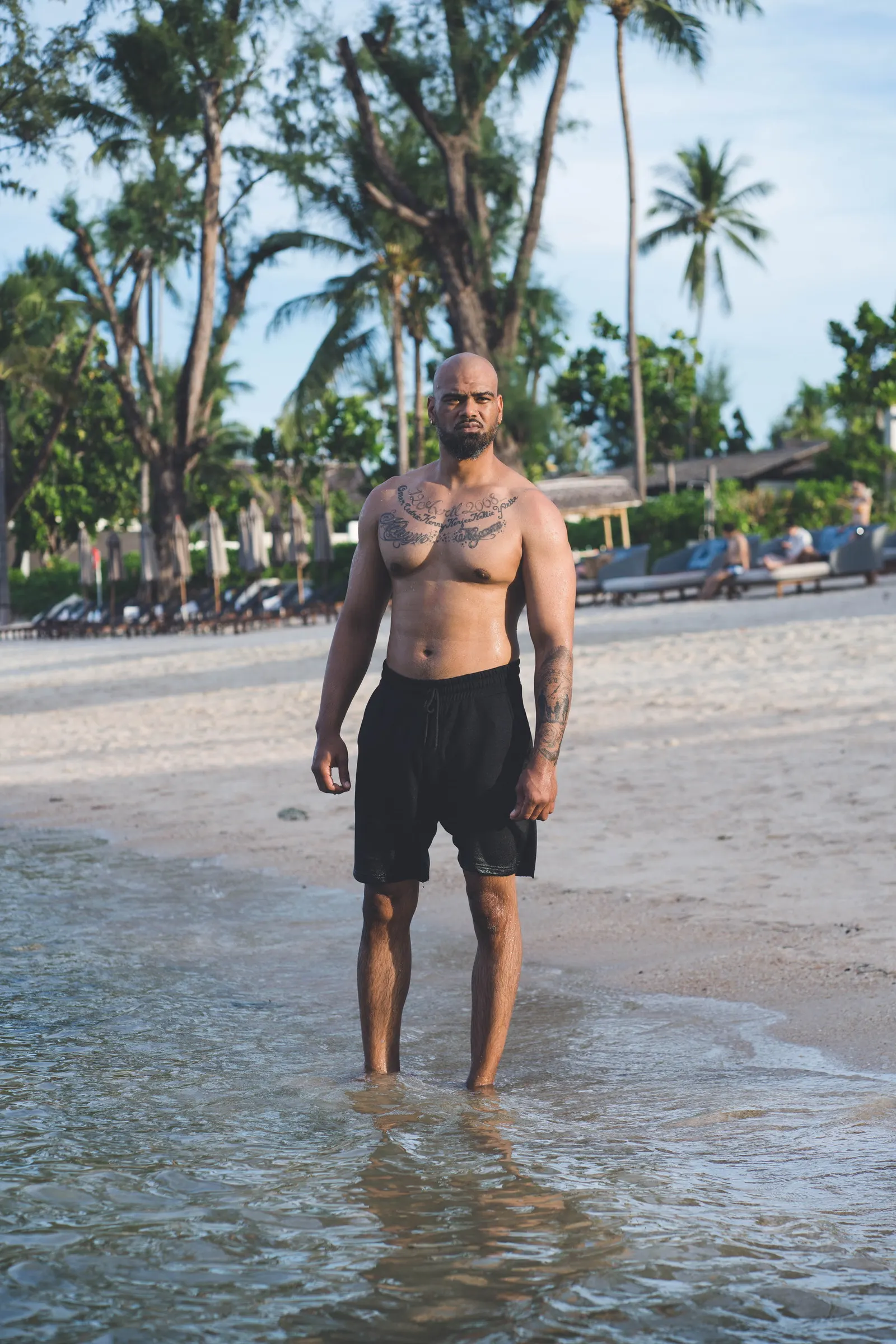 Un homme debout dans l’eau sur une plage bordée de cocotiers