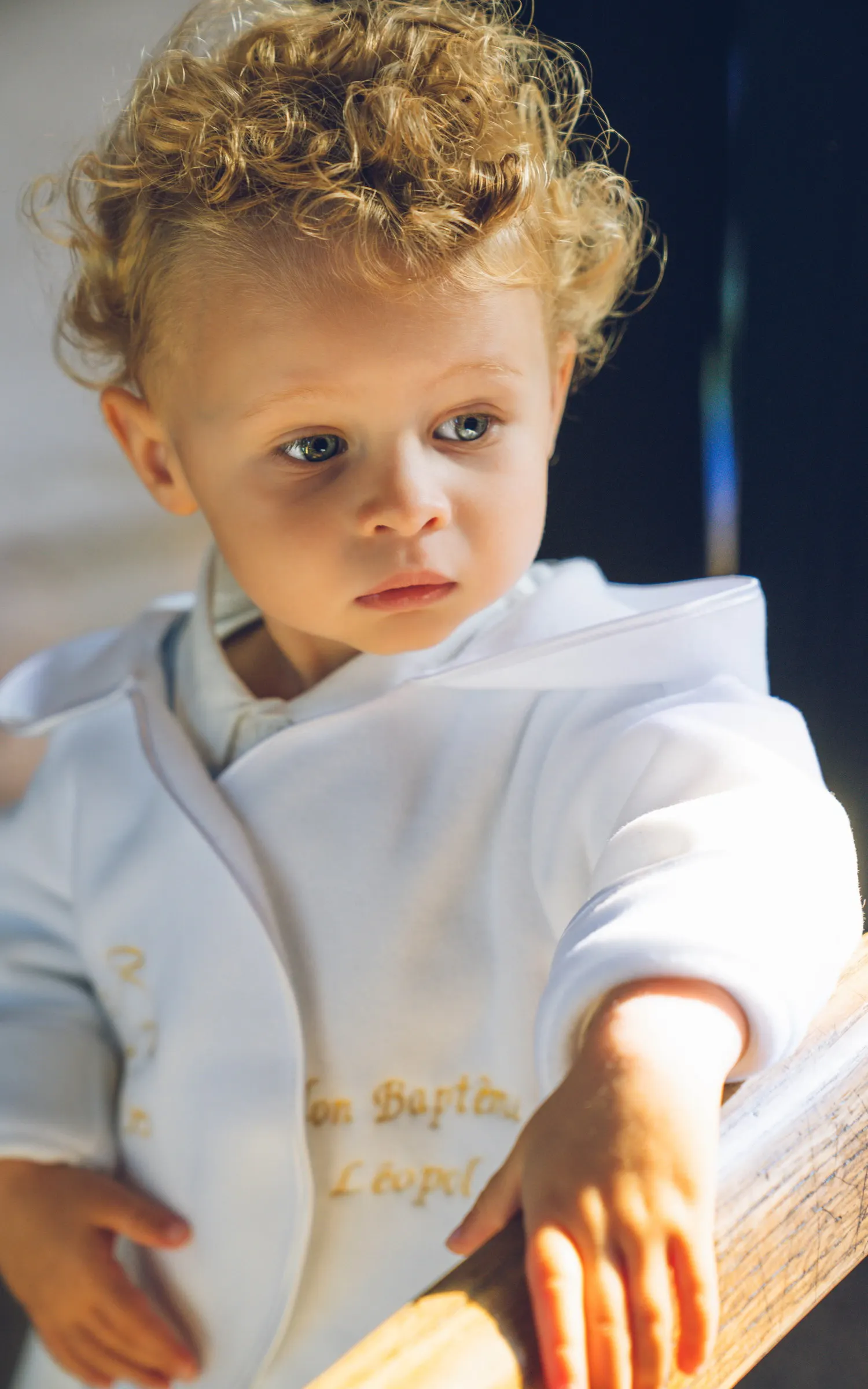 Un jeune enfant en tenue de baptême, la main posée sur un livre