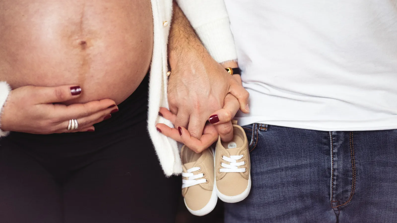 Les mains des deux parents tenant ensemble une paire de petites chaussures