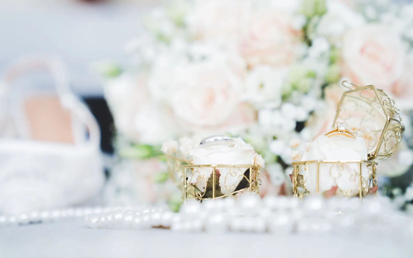 Le bouquet de roses pâles, les bijoux et les perles posés avant la cérémonie