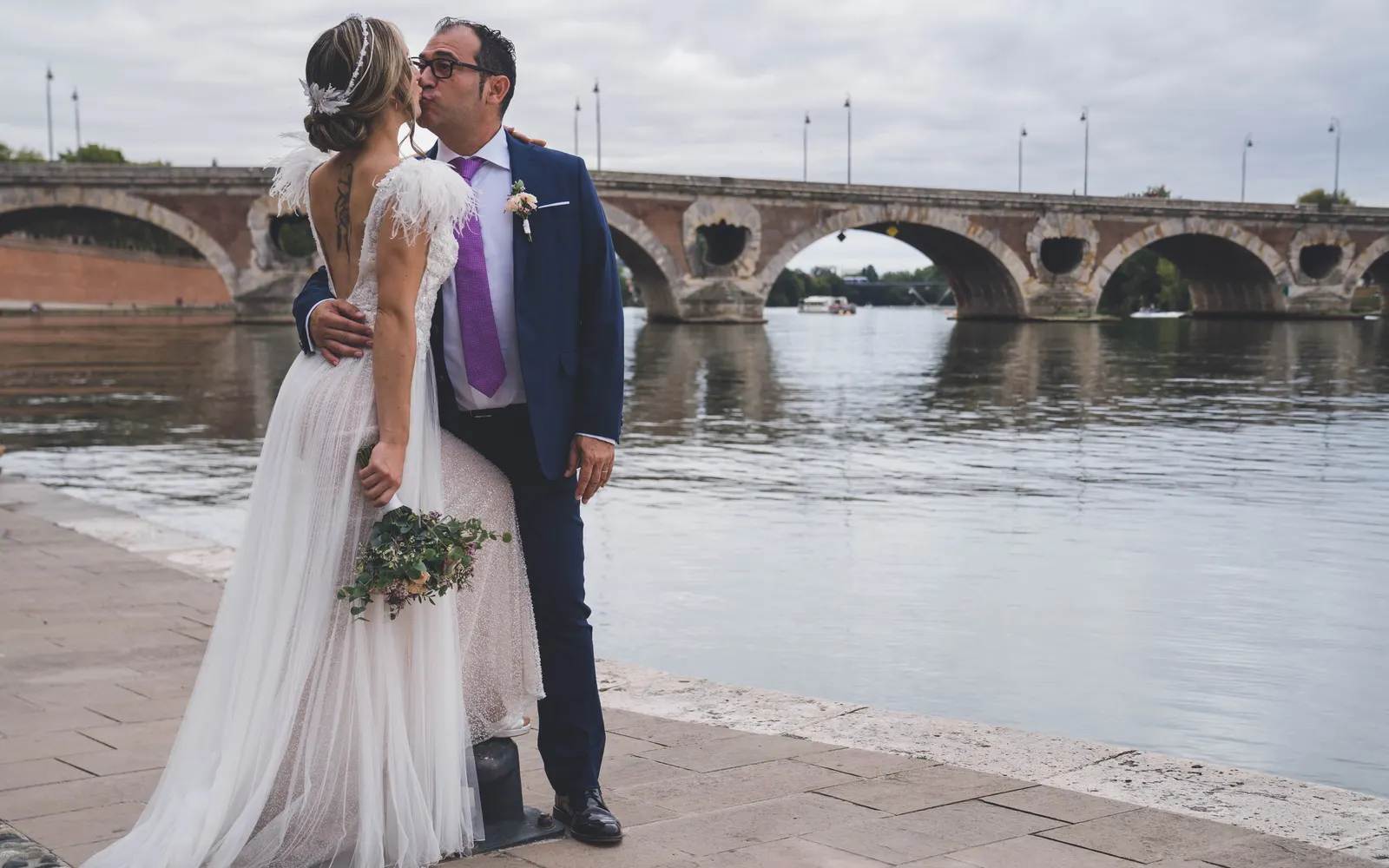 Les mariés au bord de l’eau, un pont de pierre derrière eux