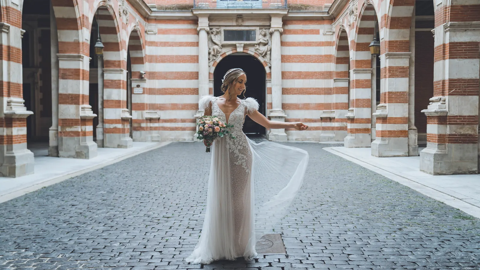 La mariée seule sous des arcades de brique rouge et blanche