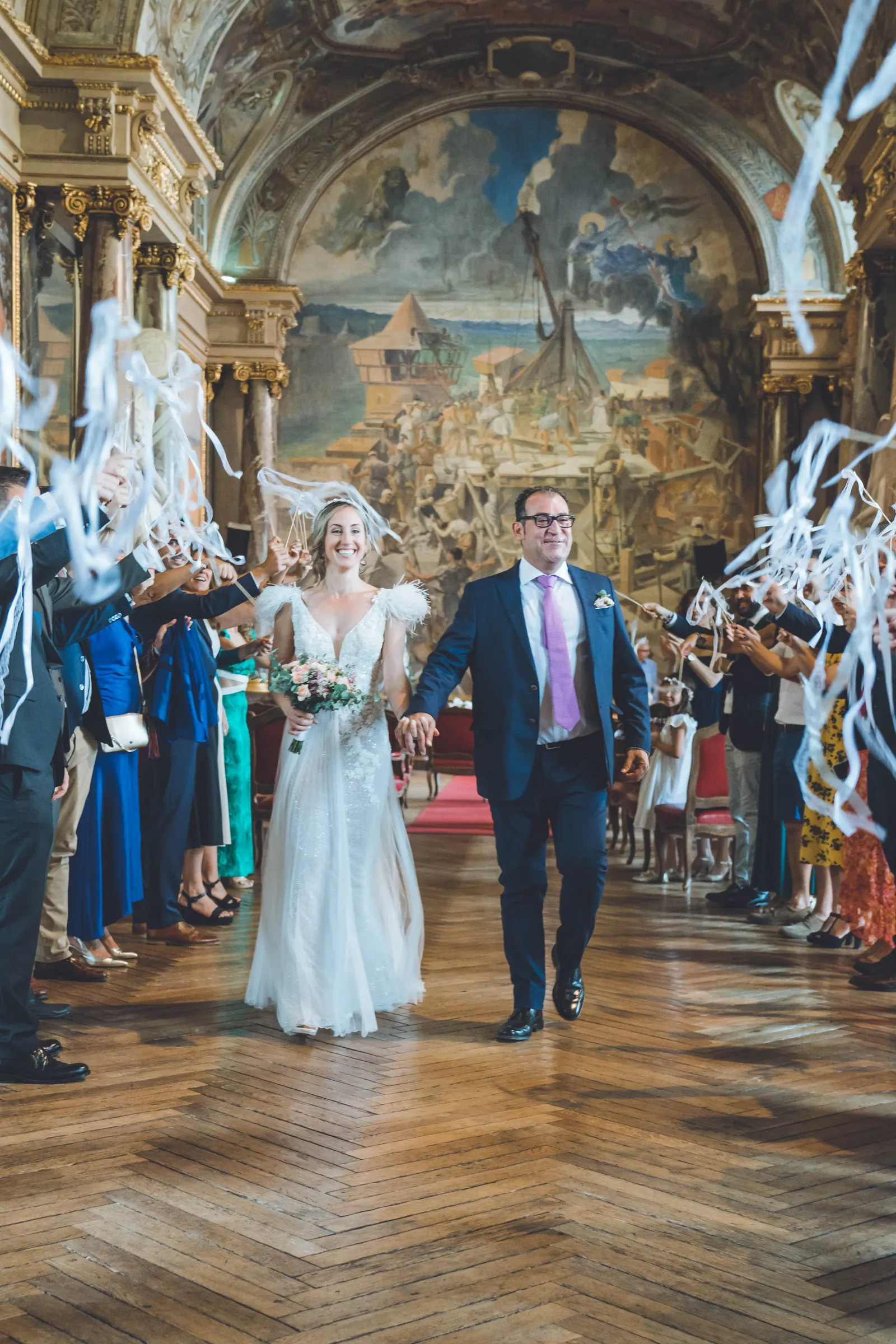 Les mariés sous une pluie de confettis, les invités tout autour
