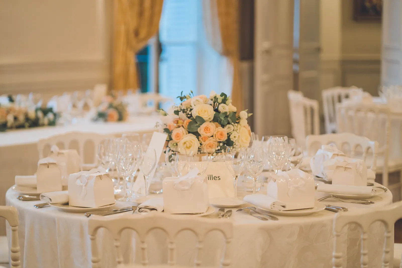 Une table dressée pour le repas, centre de table fleuri, dans une salle aux dorures