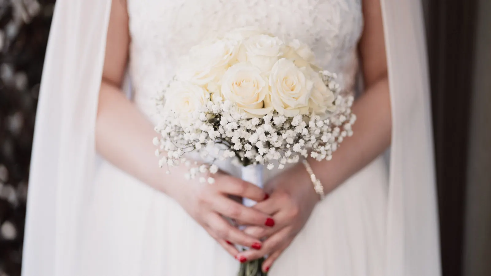 La mariée de dos, serre-tête orné, tenant son bouquet blanc