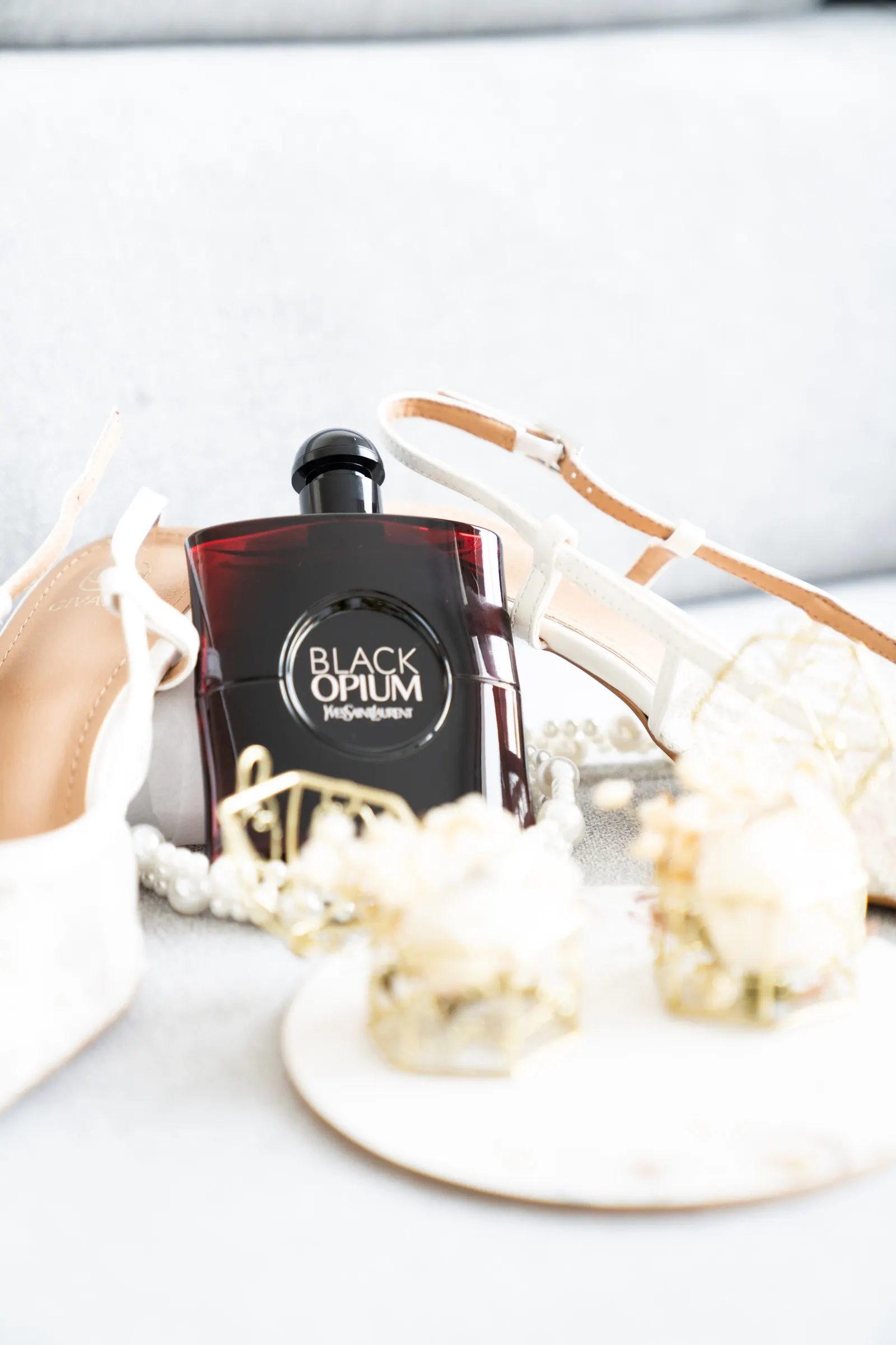Un flacon de parfum posé entre les escarpins, les perles et les bijoux de la mariée