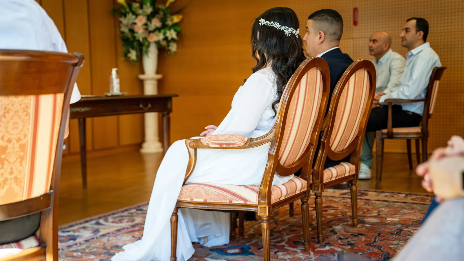 Les mariés assis pendant la cérémonie, les invités derrière eux